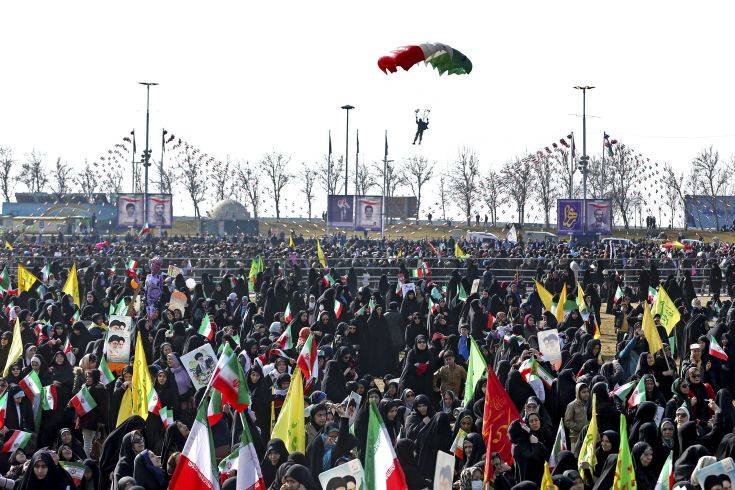 An Iranian paratrooper descends among people in a rally marking the 39th anniversary of Iran's 1979 Islamic Revolution, in Tehran, Iran, Sunday, Feb. 11, 2018. Hundreds of thousands of Iranians rallied on the streets Sunday to mark the anniversary, just weeks after anti-government protests rocked cities across the country. (AP Photo/Ebrahim Noroozi)
